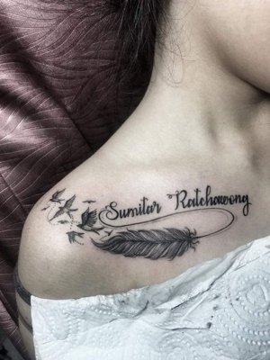 Tatouage plume avec des écritures et des oiseaux sur le haut de la poitrine